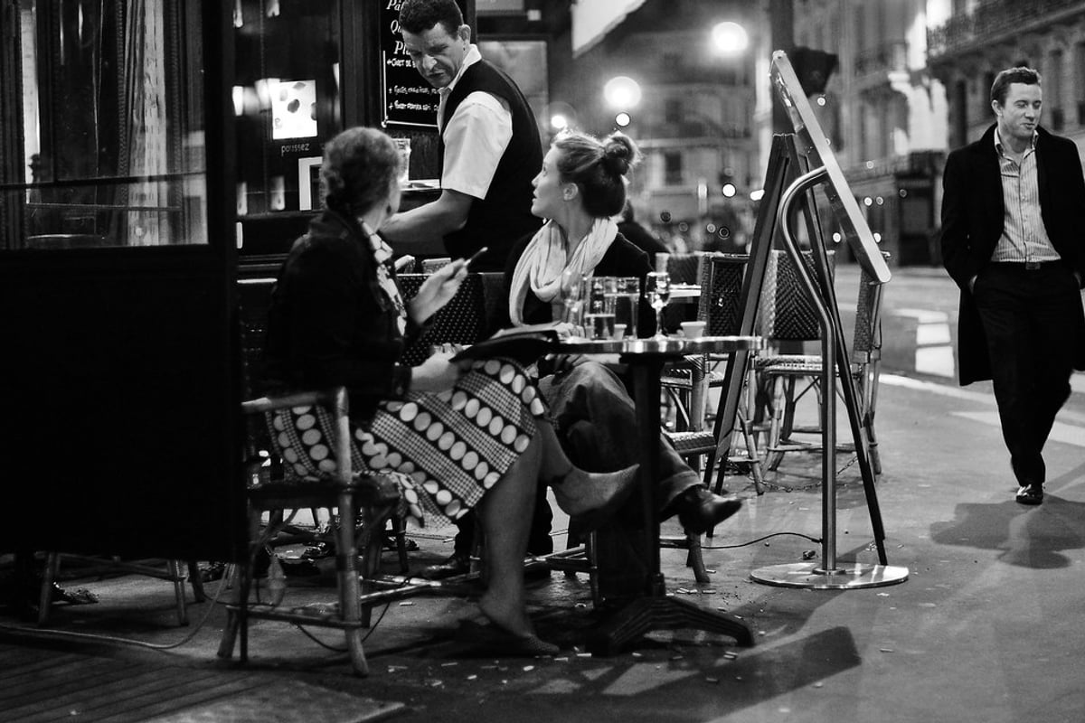Twee mensen in gesprek op een caféterras in de avond