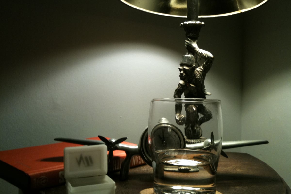 Een nachtkastje met lamp en een glas in het donker